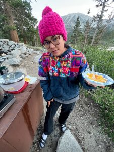 Dani Kaneshiro stands outside with a plate of food
